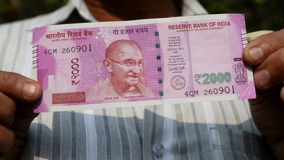 An Indian man displays a new 2,000 rupee note after exchanging his old 500 and 1,000 rupee notes at a bank in New Delhi on November 10, 2016