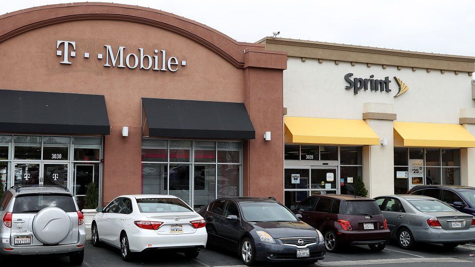 A T-Mobile and Sprint store sit side-by-side in a strip mall.