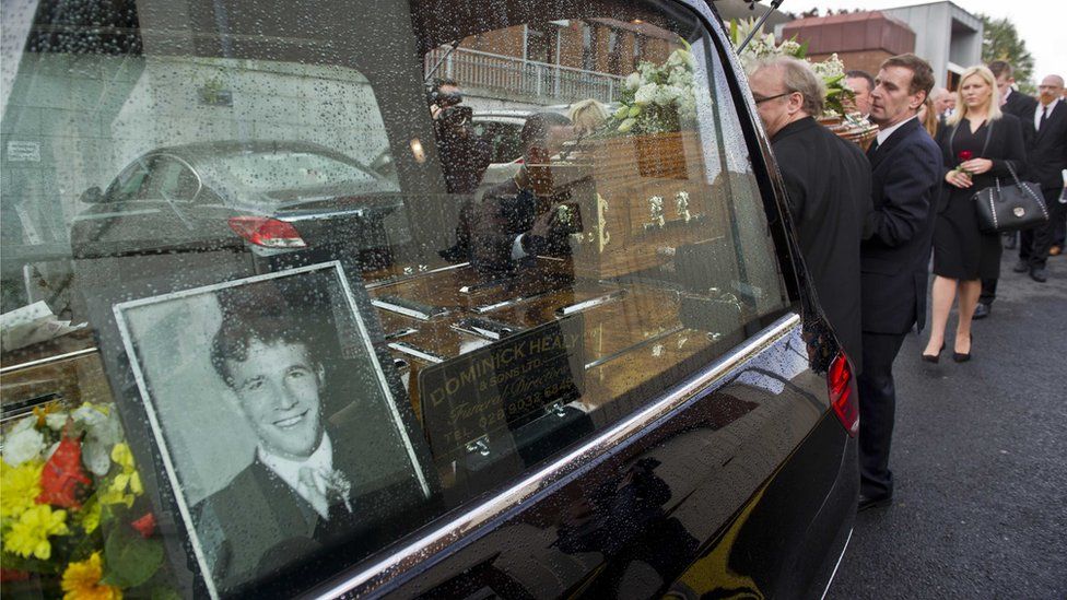 The coffin of Seamus Wright is placed into a hearse at his funeral