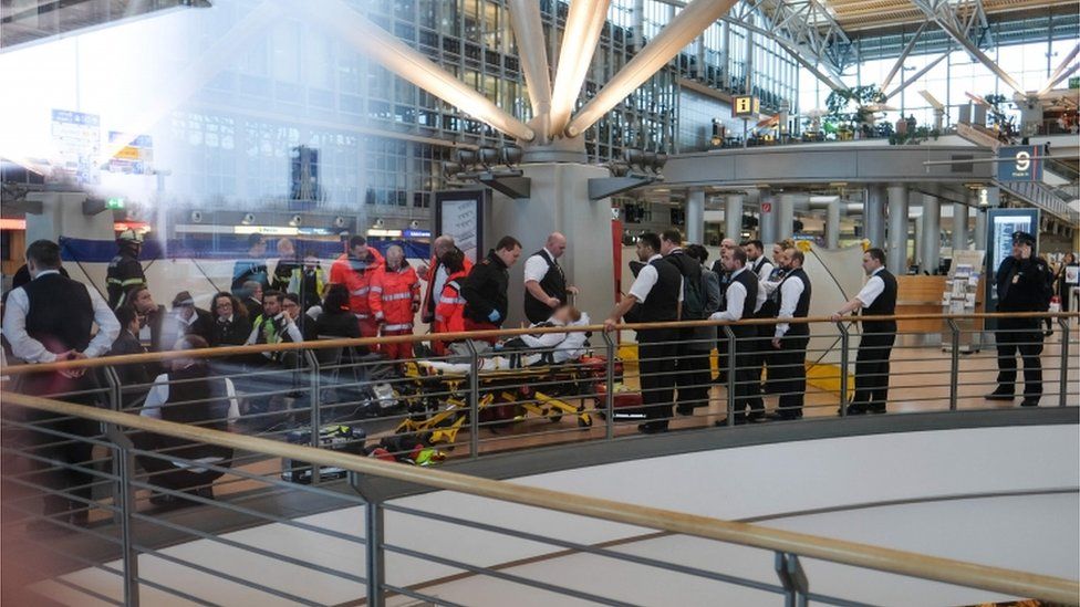 Firefighters take care of a person on a stretcher inside Hamburg airport on 12 February 2017