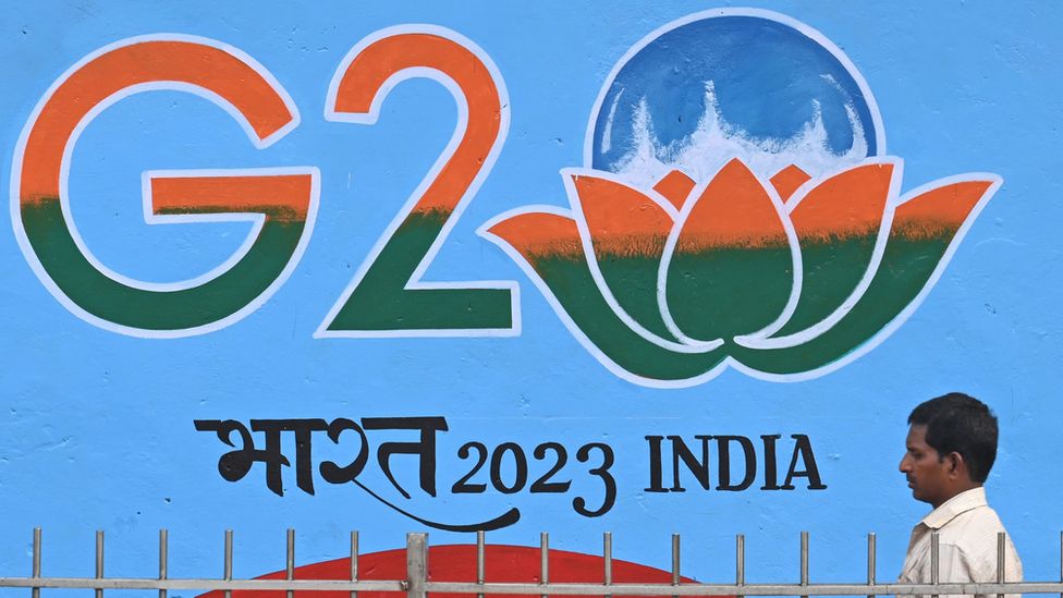 Man walks past sign in New Delhi advertising G20 summit