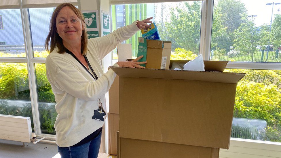 Photo shows Gill Atkinson at Harlow College, opening a big delivery of period products and smiling.