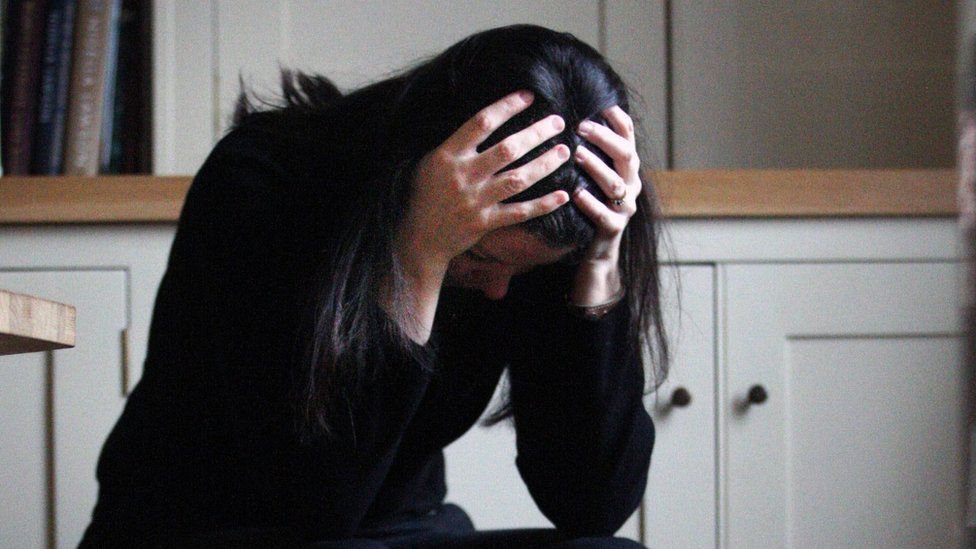 A woman looking distraught, with her hands on her head