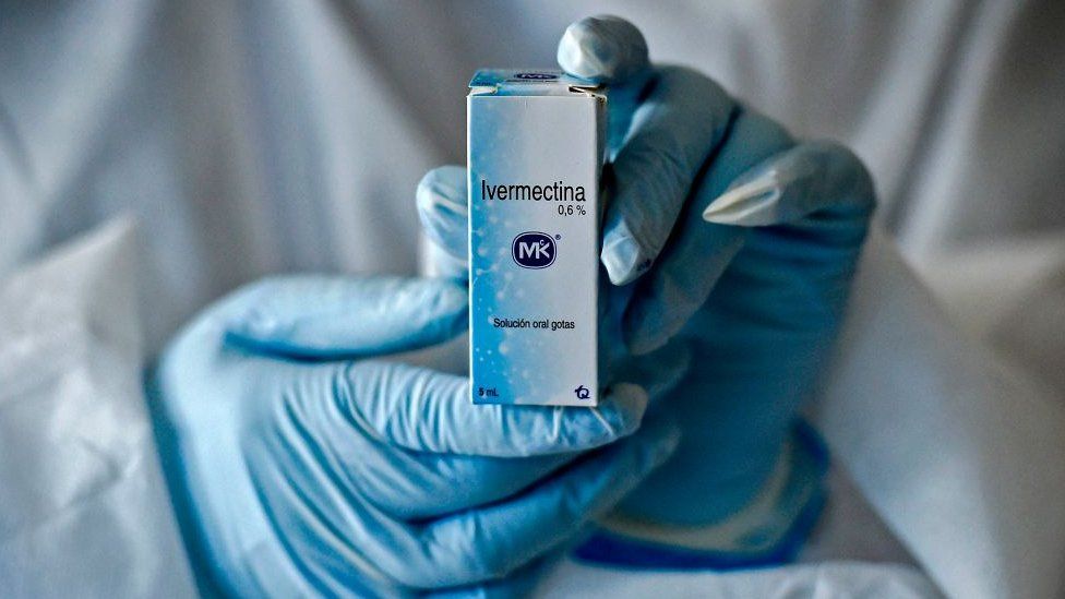 A health worker shows a box containing a bottle of Ivermectin