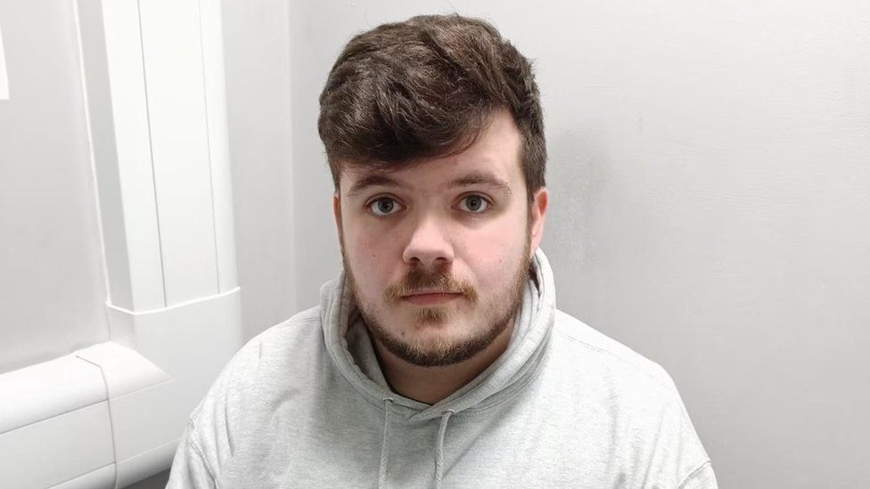 Police custody image of Jacob Crimi-Appleby, a young man with brown curly hair and a beard