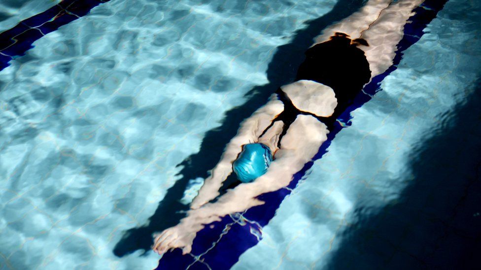 A file photograph shows a woman swimming underwater in a swimming pool