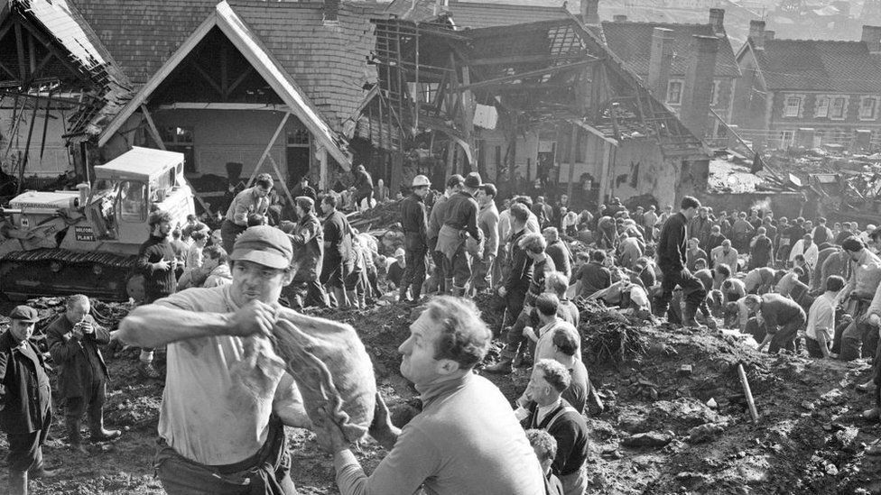 Local men and the emergency services hastily dig through the mud for survivors at The Pantglas Junior School