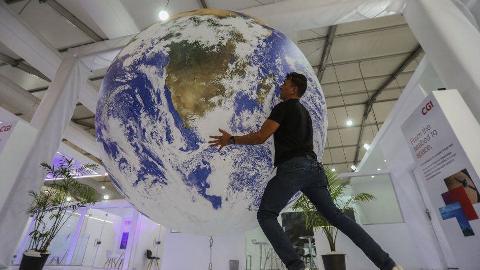 Một người đàn ông cầm quả địa cầu tại gian hàng ở COP27