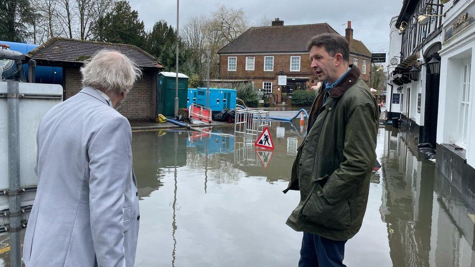 Gareth Williams and an unknown man standing in flood water in the High Street, Chalfont St Peter