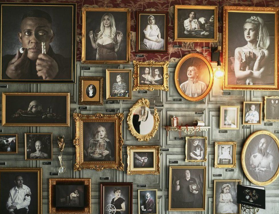 A selection of photos in old fashioned ornate gold frames on a wood-panel effect wall