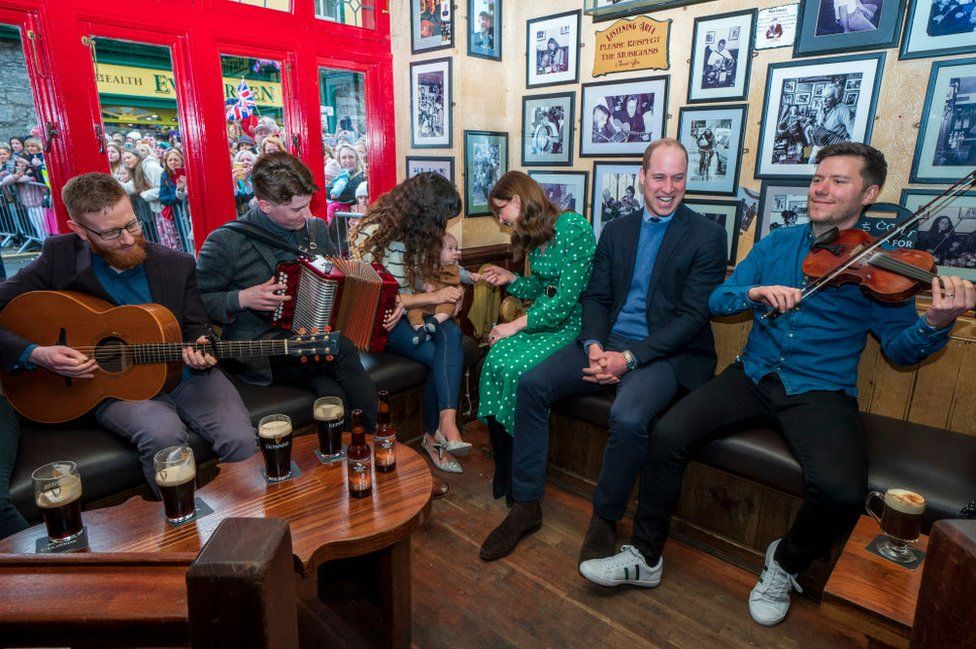 William listens to musicians play traditional Irish music while Kate speaks to a mother and baby in the Tig Cóilí pub in Galway