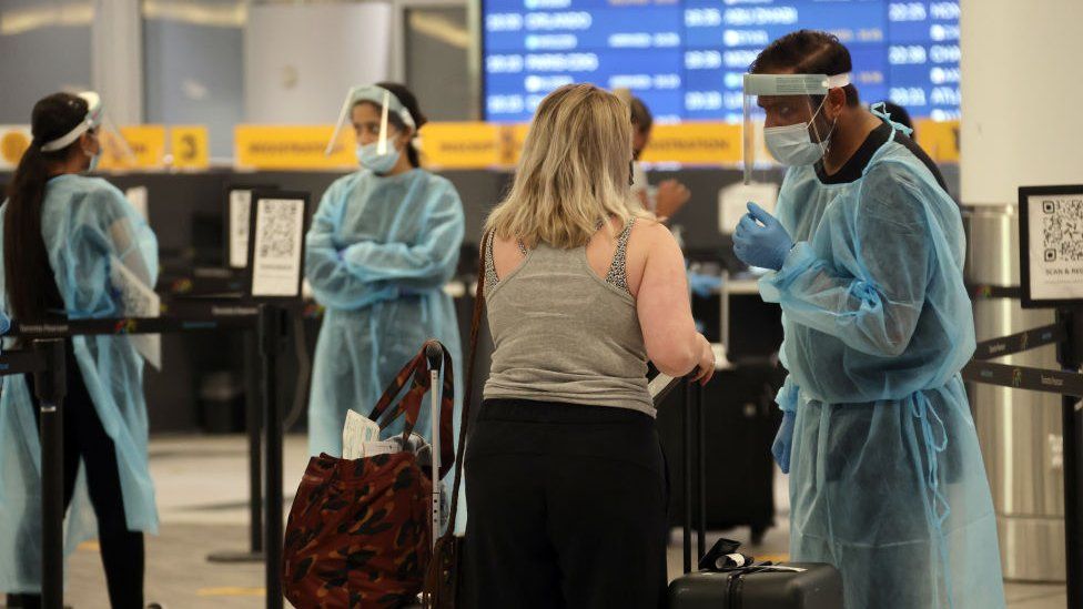 A healthcare worker directs an arriving traveller at Toronto Pearson International Airport