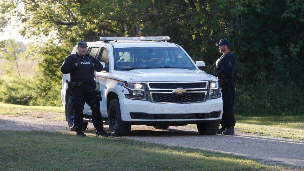 Royal Canadian Mounted Police officers stand next to a police vehicle outside the house where one of the stabbing victims was found in Weldon, Saskatchewan, Canada, on September 6, 2022