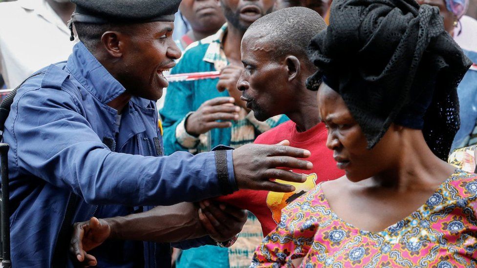 A Congolese police officer controls internally displaced people at a polling station near Goma in North Kivu province. Photo: 20 December 2023