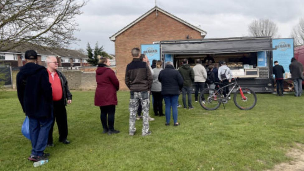 Residents queue for a burger van