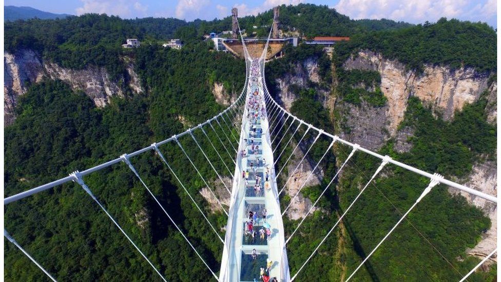 Visitors walk across a glass-floor suspension bridge in Zhangjiajie in southern China's Hunan Province Saturday, Aug. 20, 2016
