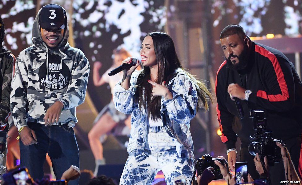 Demi on stage with Chance the Rapper and DJ Khaled