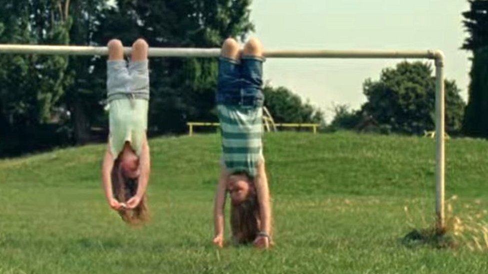 Undated screen grab from Advertising Standards Agency of Dairylea TV advert which shows two girls hanging upside down from a football goal before one opened the cheese triangle snack and ate it, has been banned following complaints that it could encourage unsafe behaviour.