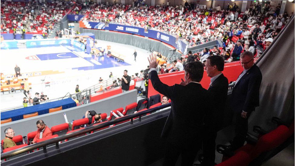 US Secretary of State Antony Blinken (L) waves next to US Ambassador to China Nicholas Burns (C) and US Consulate General in Shanghai Scott Walker (R) while attending a basketball game between the Shanghai Sharks and the Zhejiang Golden Bulls at the Shanghai Indoor Stadium in Shanghai on April 24, 2024