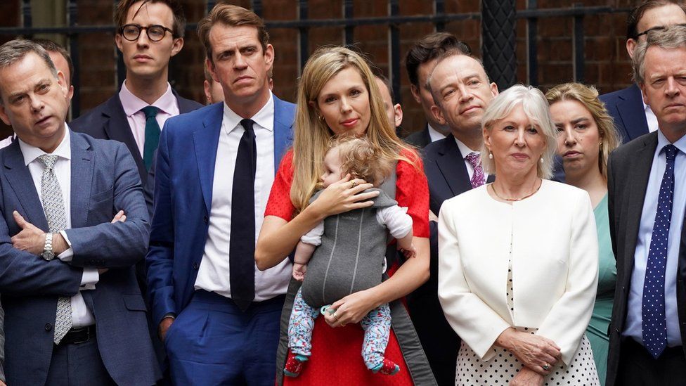 Carrie Johnson, the wife of Prime Minister Boris Johnson, cradles their daughter Romy as she listens to him read a statement outside 10 Downing Street.