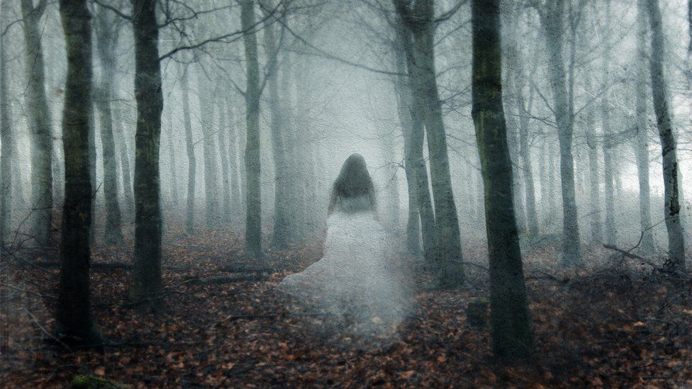 A ghostly woman walking through a foggy forest