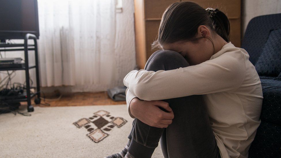 A teenage girl hugging her legs