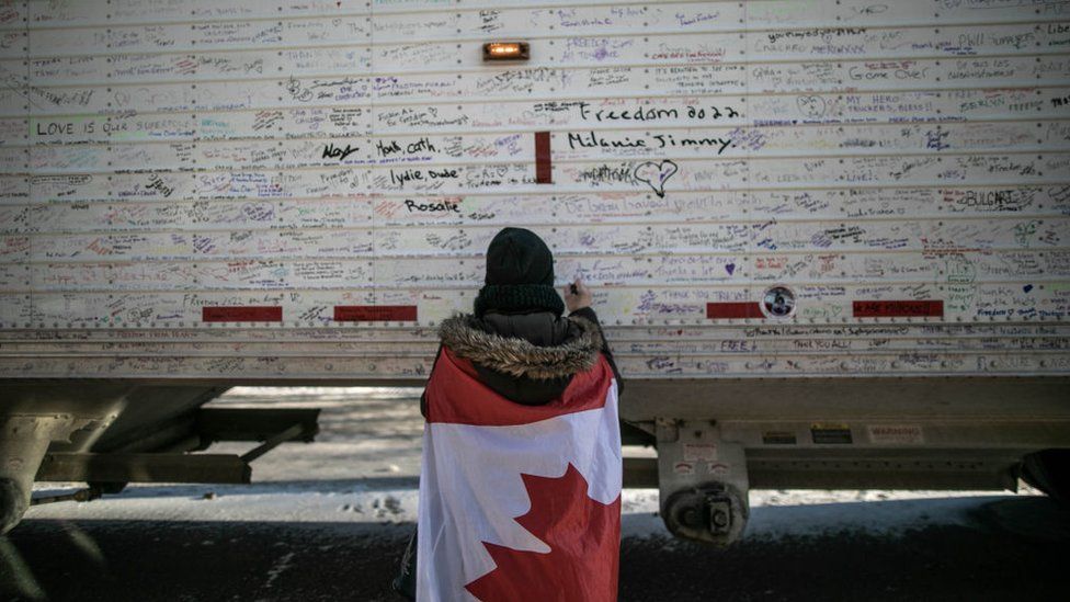 Женщина пишет заметки на грузовиках, чтобы поддержать дальнобойщиков, продолжающих свой протест против введения вакцины против коронавируса в стране, Оттава, Канада, 13 февраля 2022 года.