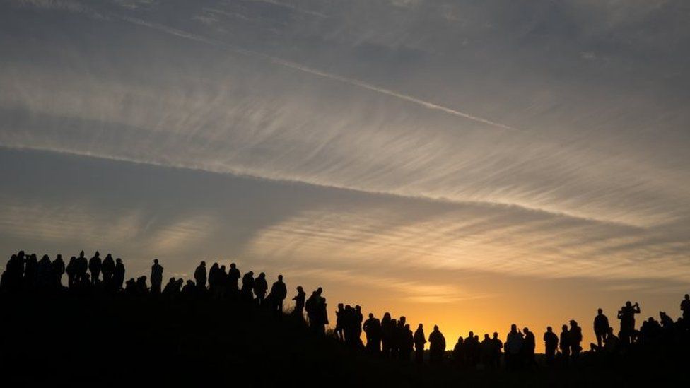 People standing on hill watching sunrise