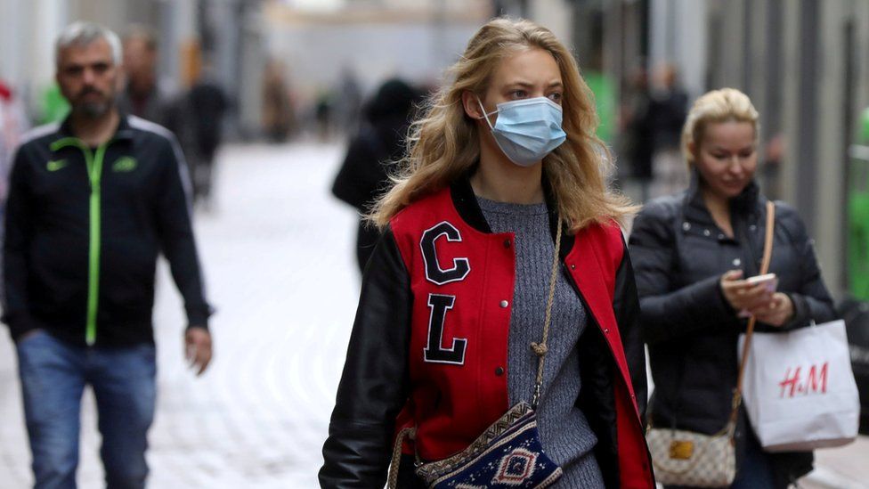 People with and without protective masks walk on the street in Amsterdam