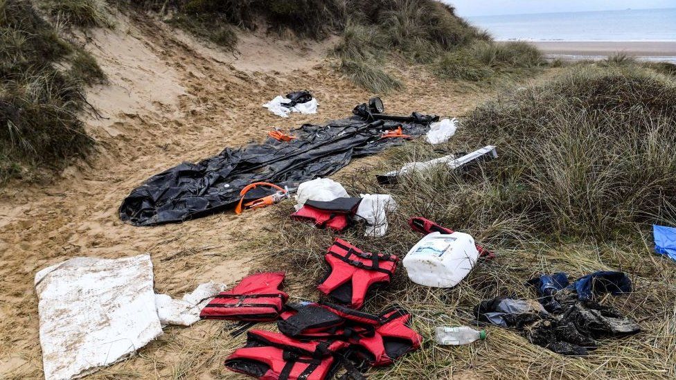 Life jackets and a deflated dinghy lie on a beach near Calais