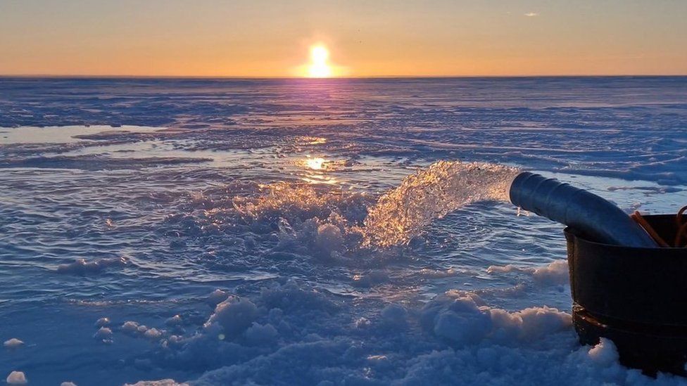 Seawater pump floods the surface of the sea ice with seawater as the Sun sets