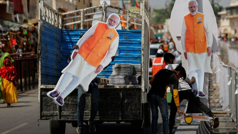 A person carries a cut-out of India’s Prime Minister Narendra Modi, ahead of his election campaign rally, in Ayodhya, India