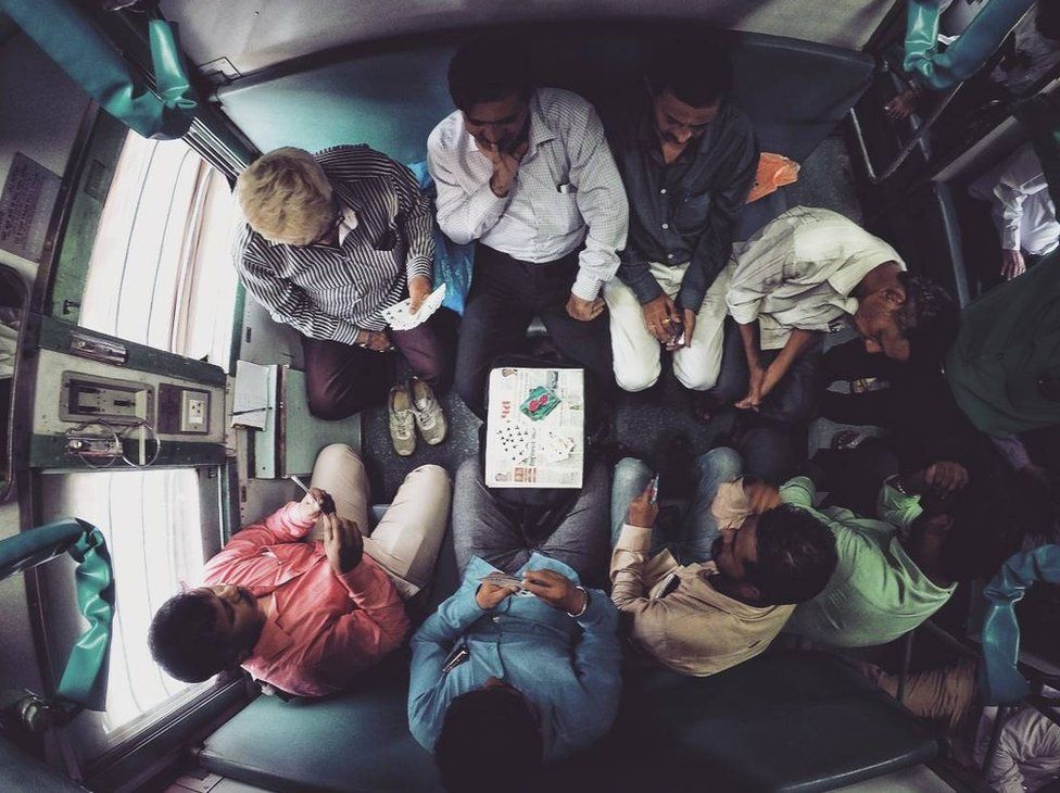 Passengers playing cards on a train.