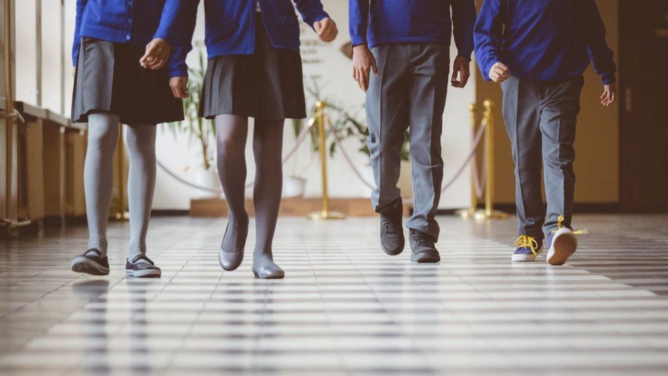 Cropped image of school kids in uniform walking together in a row through corridor