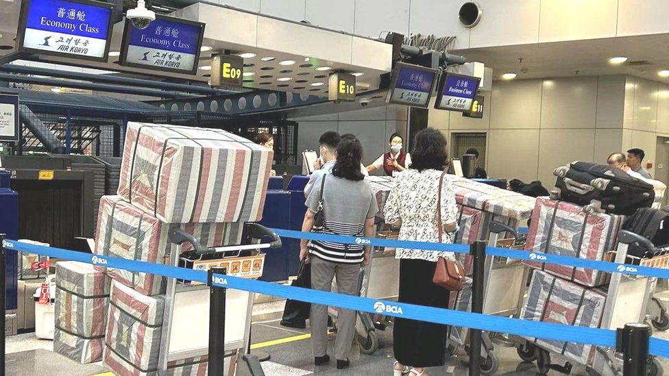 Северокорейцы стоят в очереди у стоек регистрации в международном аэропорту Пекина, 22 августа
