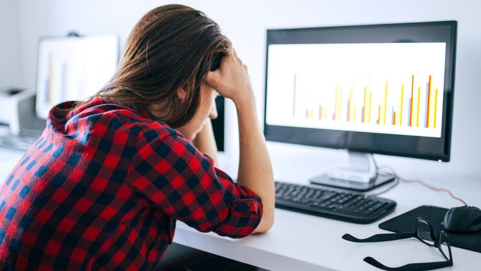 Stock image of a woman at a computer looking at a graph and looking upset