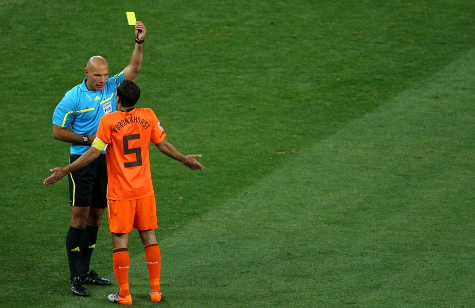 Howard Webb shows a yellow card to Van Bronckhorst in the 2010 World Cup Final in South Africa, between the Netherlands and Spain.
