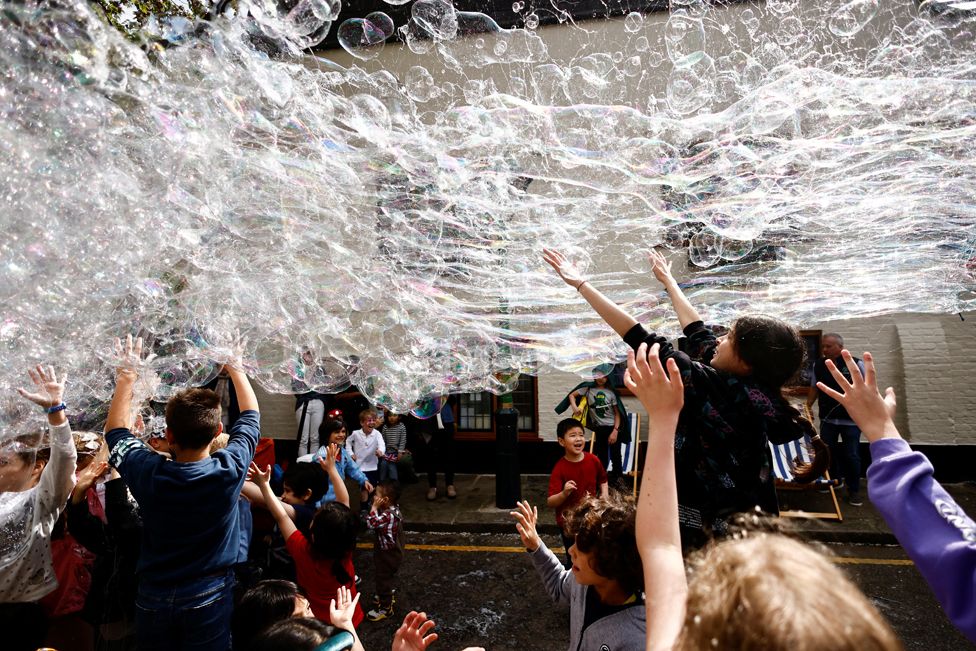 Children play with bubbles at a Big Lunch event to celebrate the coronation of Britain's King Charles, at Gloucester Street in London, Britain, May 7, 2023