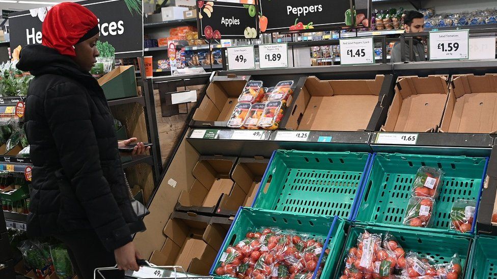 Женщина смотрит на помидоры в супермаркете