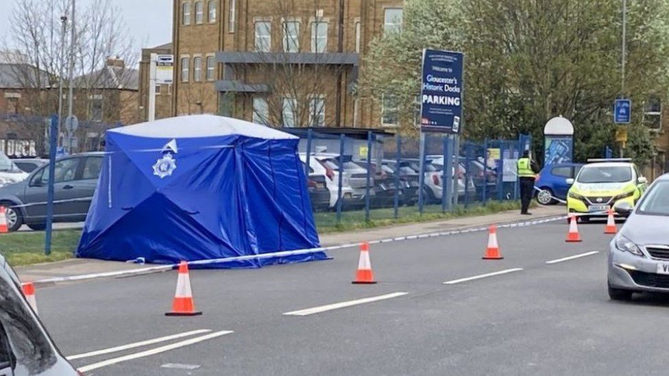 A blue police tent on a main road with police, a police car and cones