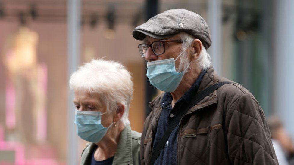 Two people wearing masks as they walk in Manchester