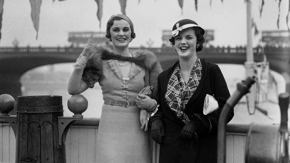 English socialite Margaret Whigham (later Duchess of Argyll, 1912 - 1993, left) with a friend on board a boat travelling down the river Thames, London, June 1930
