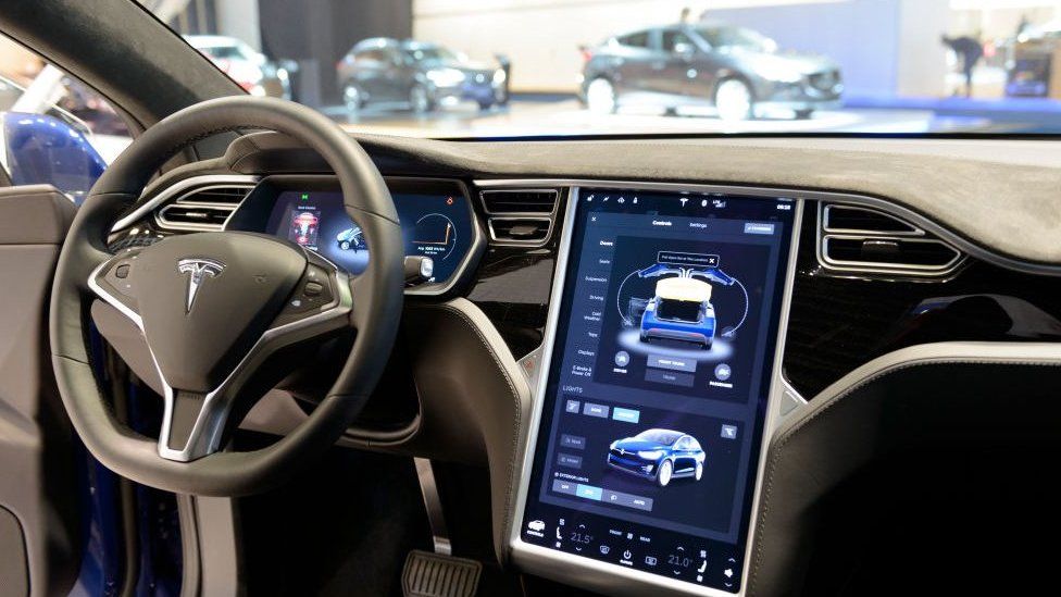 The interior on a Tesla Model S full electric luxury car with a large touch screen and dashboard screen.