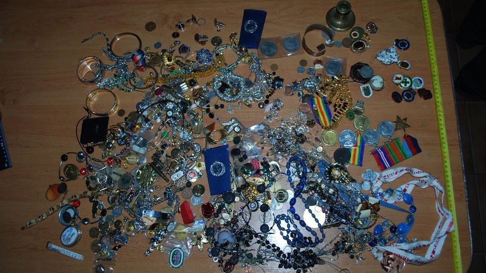 A selection of jewellery, watches, war medals on a brown table