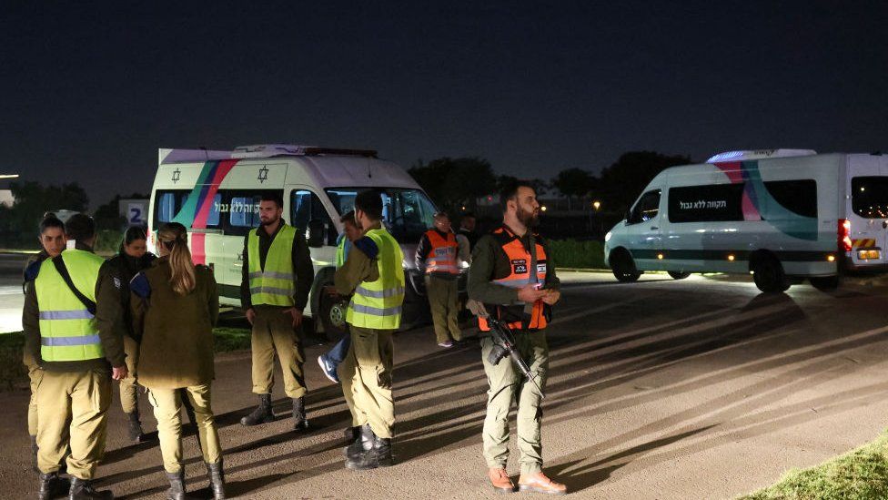 Isreali security forces stand near vehicles waiting to transport two Israeli-Russian hostages