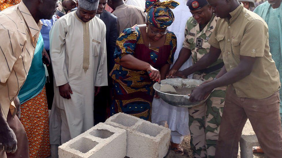 Ngozi Okonjo-Iweala using a trowel to scoop mortar from a pan