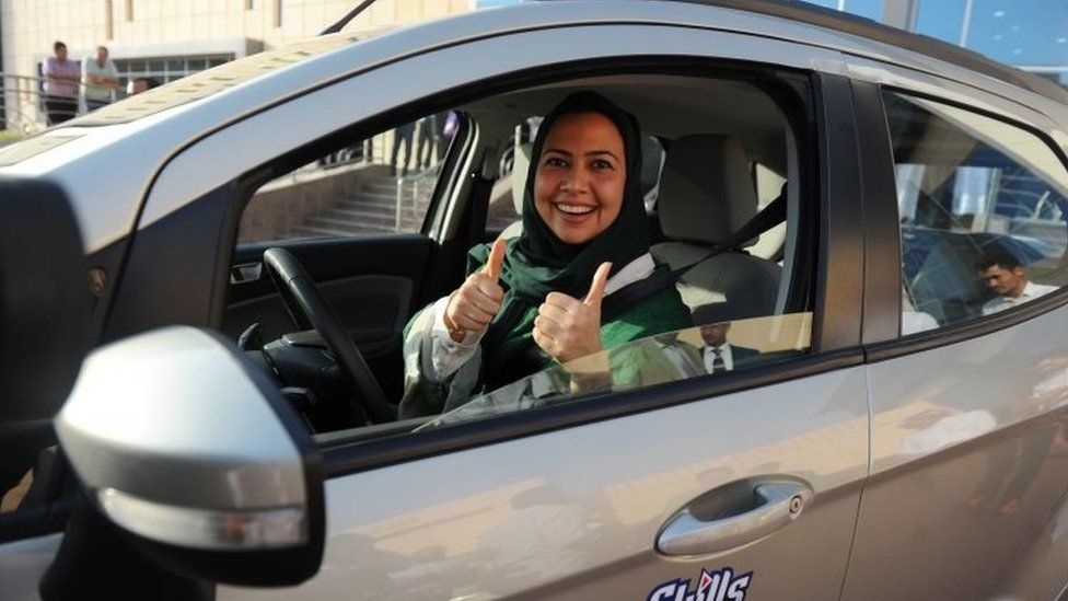 Woman behind wheel of car with thumbs up