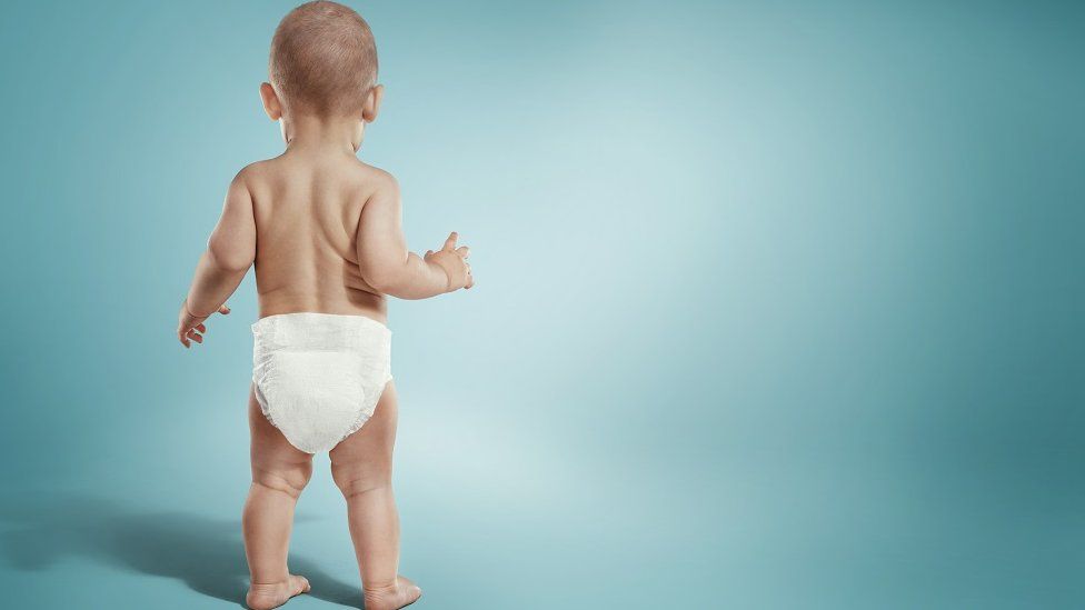 stock image of baby standing in nappy