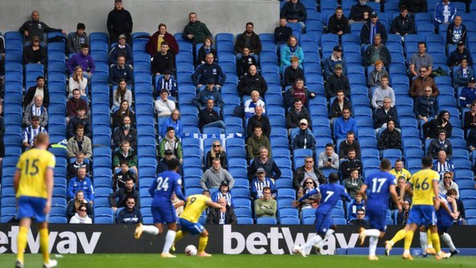 Socially-distanced fans watch a friendly between Brighton and Chelsea at the Amex Stadium