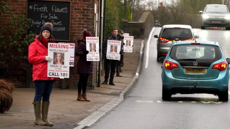People hold missing person appeal posters on road in St Michael's on Wyre, Lancashire